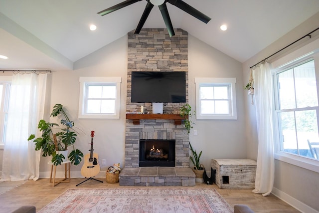 living room with hardwood / wood-style flooring, lofted ceiling with beams, a stone fireplace, and a wealth of natural light