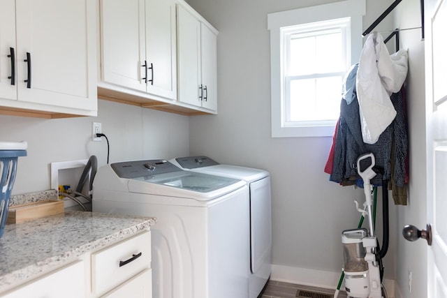 clothes washing area with cabinets and washing machine and clothes dryer