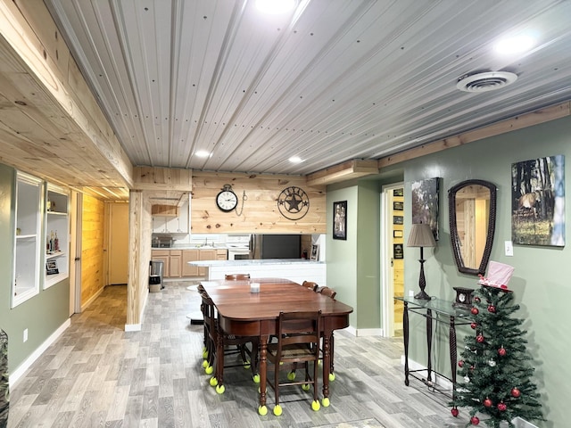 dining space featuring wooden ceiling, sink, wooden walls, built in features, and light wood-type flooring