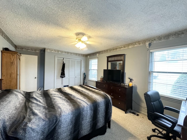bedroom with a textured ceiling, ceiling fan, light carpet, and a closet