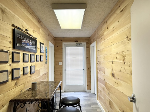 entryway featuring wooden walls, a textured ceiling, and hardwood / wood-style flooring