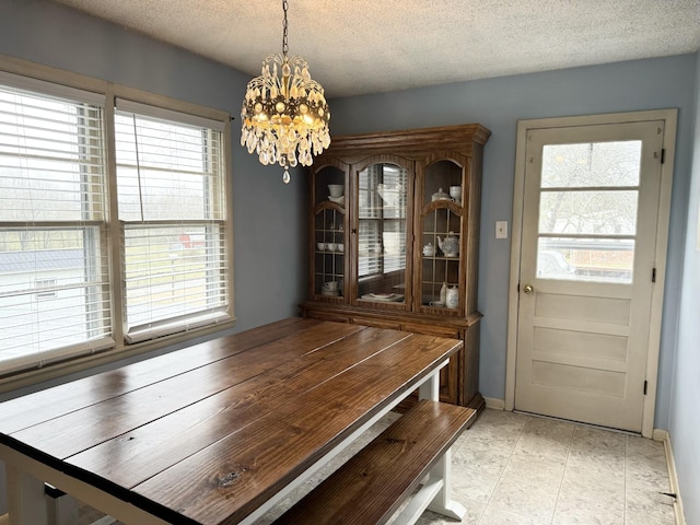 unfurnished dining area with a textured ceiling and a notable chandelier