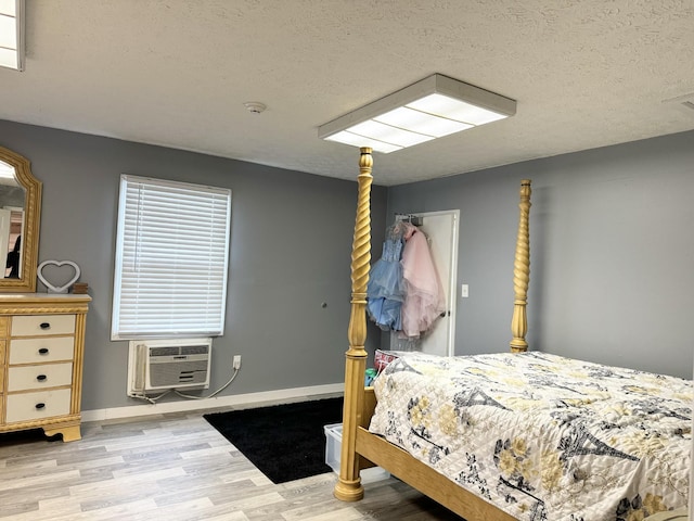 bedroom featuring wood-type flooring, a textured ceiling, and a wall mounted AC