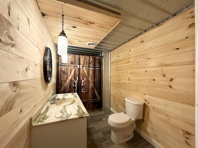 bathroom featuring wood-type flooring, toilet, wooden walls, vanity, and wood ceiling