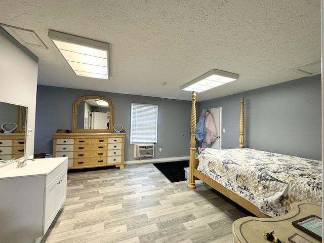 bedroom featuring a wall unit AC, a textured ceiling, and light wood-type flooring