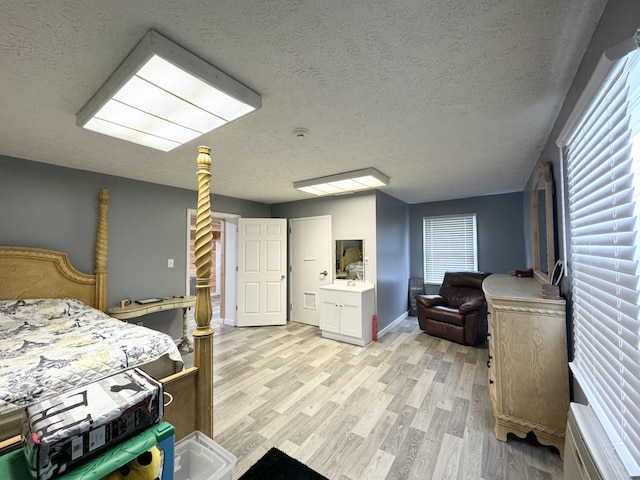 bedroom featuring sink, a textured ceiling, and light hardwood / wood-style flooring