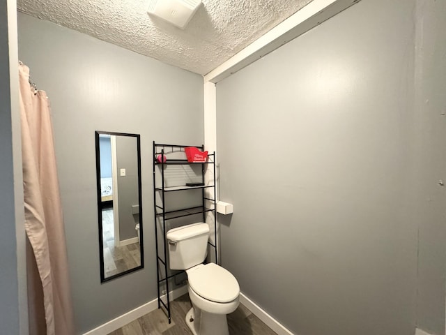 bathroom with a textured ceiling, hardwood / wood-style flooring, and toilet
