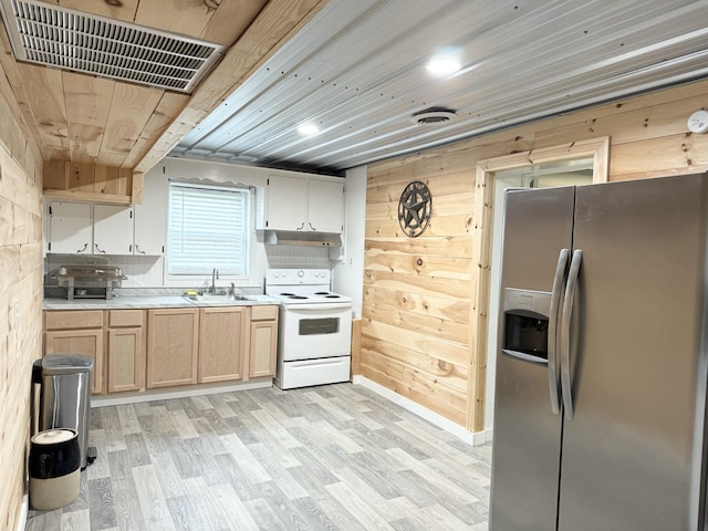 kitchen featuring stainless steel fridge, wooden walls, sink, light hardwood / wood-style flooring, and white range with electric cooktop