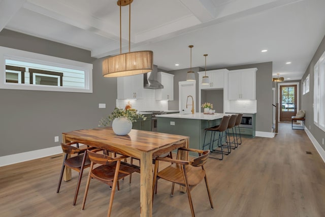 dining room with beamed ceiling, sink, and light hardwood / wood-style flooring