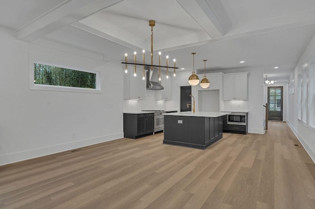 kitchen featuring built in microwave, white cabinetry, wall chimney exhaust hood, hanging light fixtures, and high end stove