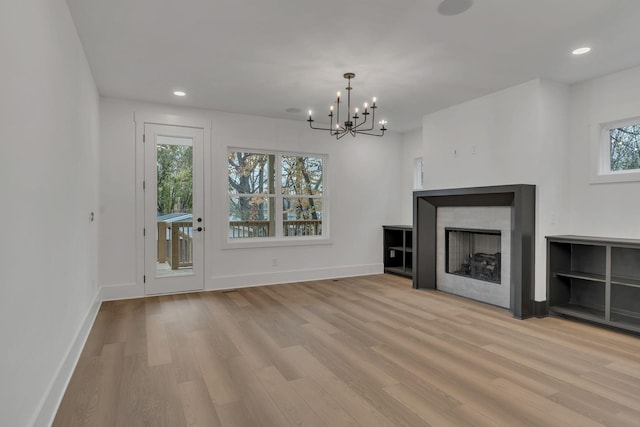 unfurnished living room with light hardwood / wood-style floors and an inviting chandelier