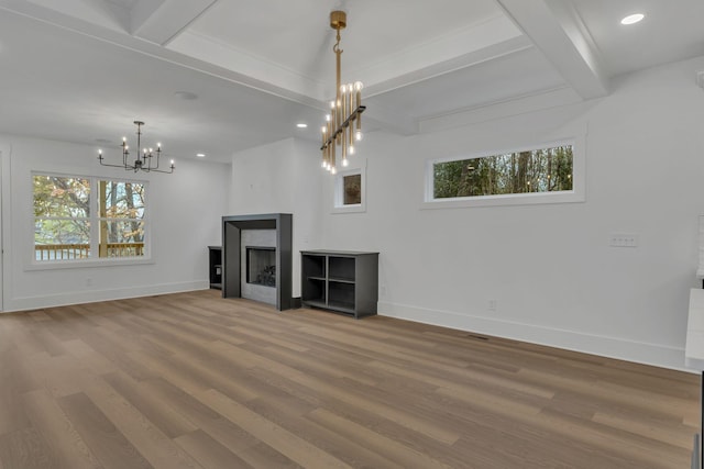 unfurnished living room featuring a chandelier, wood-type flooring, and a healthy amount of sunlight