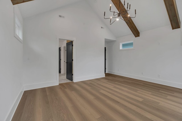 unfurnished living room featuring beamed ceiling, light hardwood / wood-style flooring, high vaulted ceiling, and a chandelier