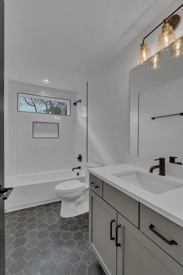 full bathroom featuring vanity, tiled shower / bath combo, and toilet