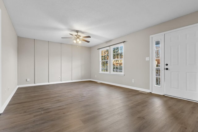 foyer with a textured ceiling, ceiling fan, and dark wood-type flooring