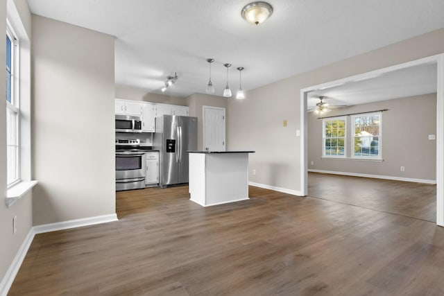 kitchen with appliances with stainless steel finishes, ceiling fan, pendant lighting, white cabinets, and dark hardwood / wood-style floors