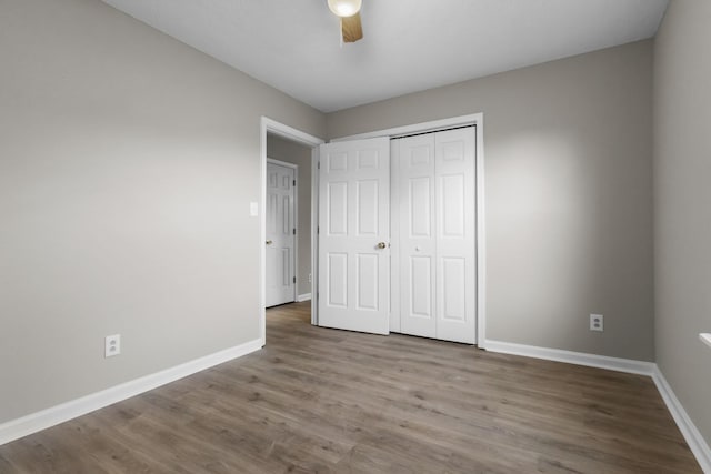 unfurnished bedroom featuring hardwood / wood-style floors, ceiling fan, and a closet