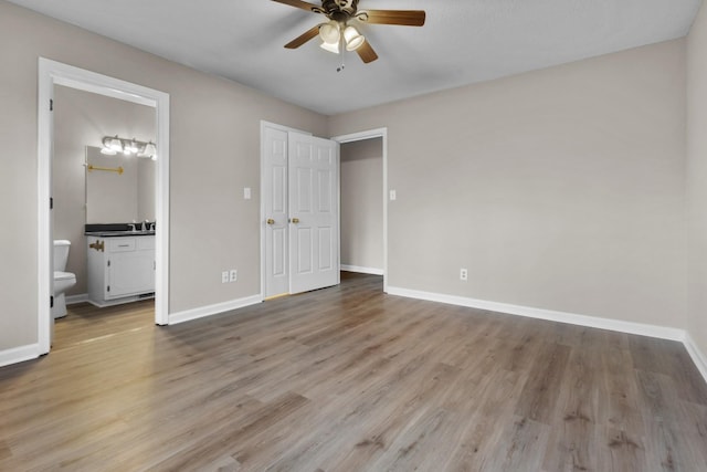 unfurnished bedroom with connected bathroom, ceiling fan, and light wood-type flooring