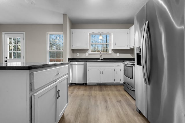 kitchen with sink, white cabinets, light hardwood / wood-style floors, and appliances with stainless steel finishes