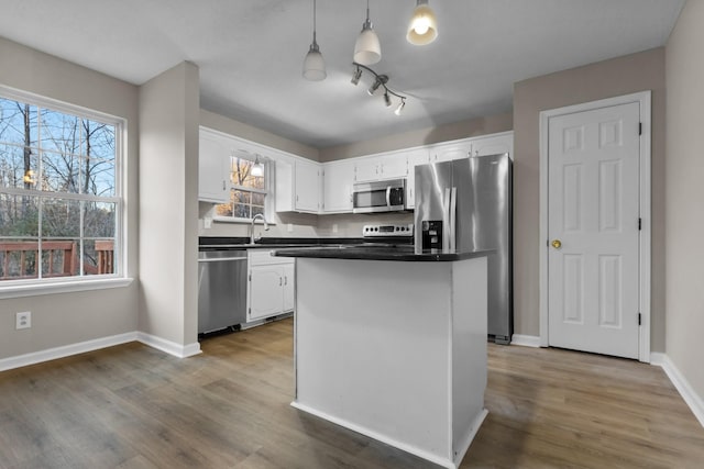 kitchen featuring appliances with stainless steel finishes, dark wood-type flooring, a center island, white cabinetry, and hanging light fixtures