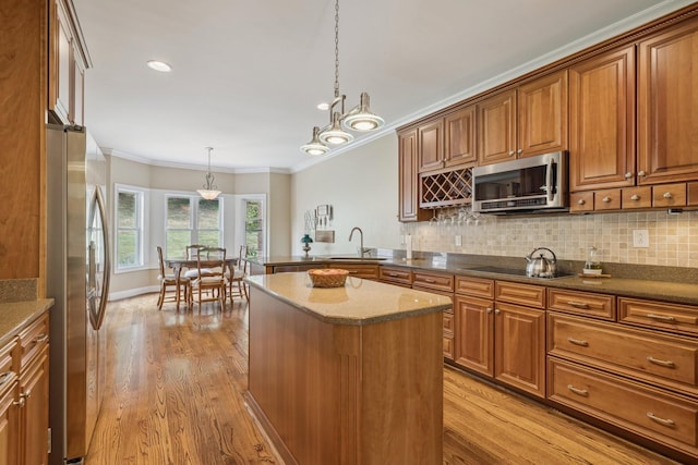 kitchen featuring pendant lighting, decorative backsplash, stainless steel appliances, and light hardwood / wood-style floors