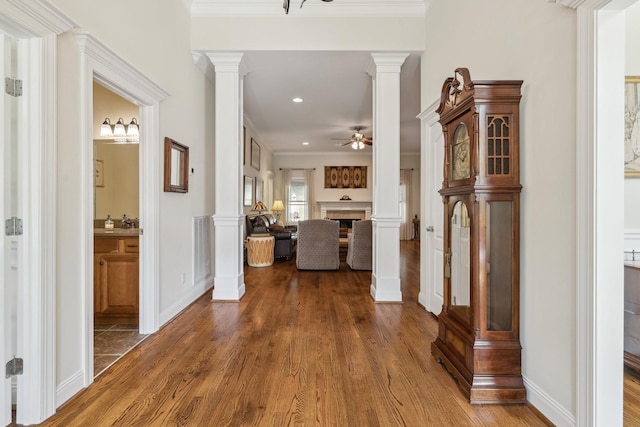 hall with decorative columns, ornamental molding, and dark hardwood / wood-style floors