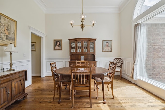 dining space featuring crown molding, light hardwood / wood-style floors, and a chandelier