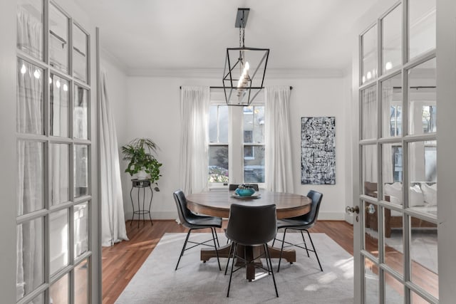 dining area with hardwood / wood-style flooring, ornamental molding, french doors, and a chandelier