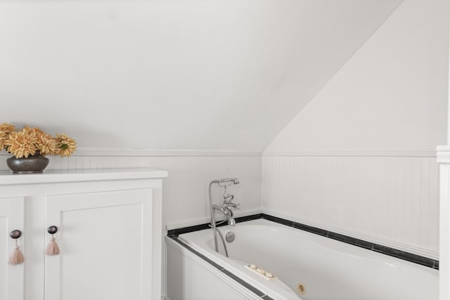 bathroom with a tub and lofted ceiling