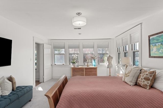 bedroom featuring light colored carpet and multiple windows