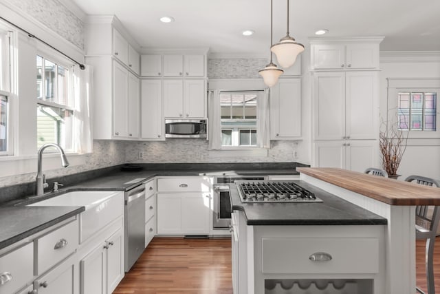 kitchen featuring a kitchen breakfast bar, stainless steel appliances, white cabinets, a center island, and hanging light fixtures