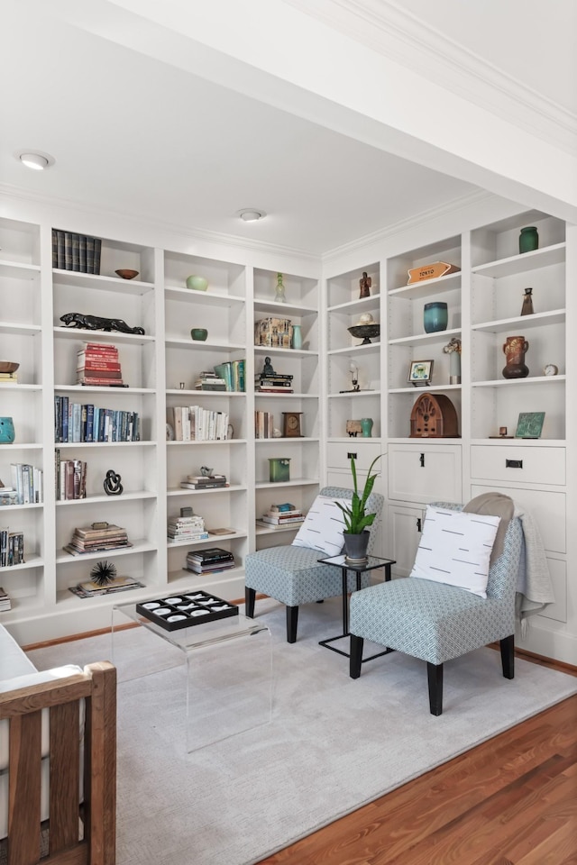 sitting room featuring wood-type flooring, built in features, and crown molding