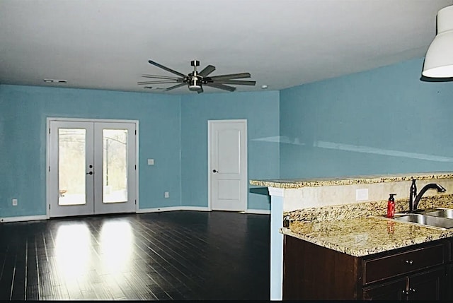 kitchen with dark hardwood / wood-style floors, sink, ceiling fan, light stone counters, and french doors