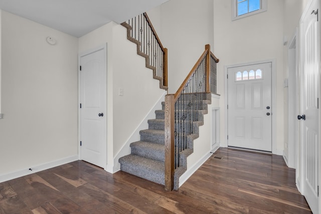 foyer entrance with dark hardwood / wood-style floors and a high ceiling