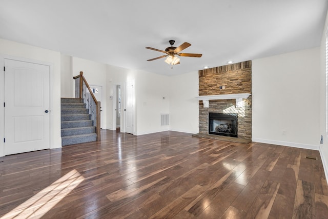 unfurnished living room with ceiling fan, dark hardwood / wood-style floors, and a stone fireplace