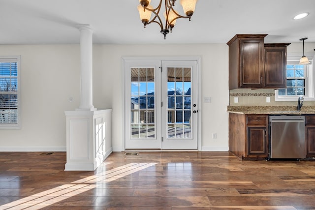 interior space featuring ornate columns, an inviting chandelier, dark brown cabinets, hanging light fixtures, and stainless steel dishwasher