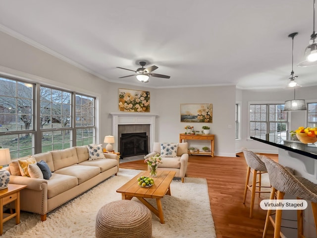 living room with light hardwood / wood-style floors, plenty of natural light, ornamental molding, and a tiled fireplace