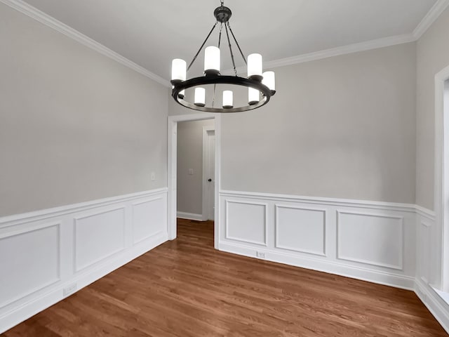 unfurnished dining area with dark hardwood / wood-style floors, ornamental molding, and a chandelier