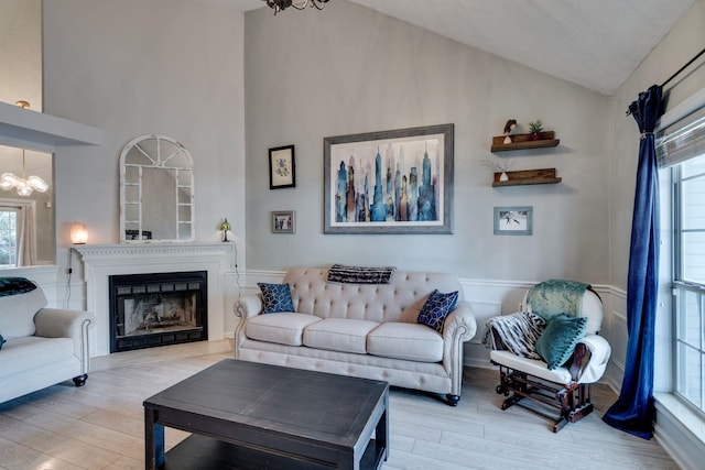 living room with vaulted ceiling, light wood-type flooring, and an inviting chandelier