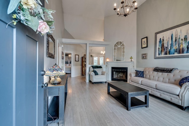 living room with high vaulted ceiling, a chandelier, and wood-type flooring