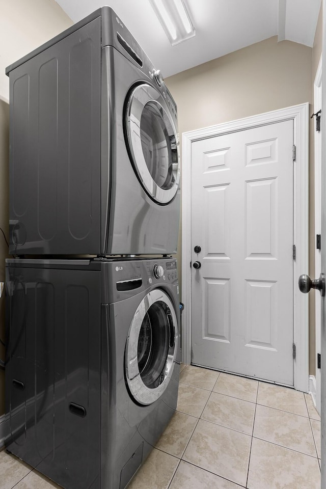 clothes washing area with light tile patterned flooring and stacked washer and dryer