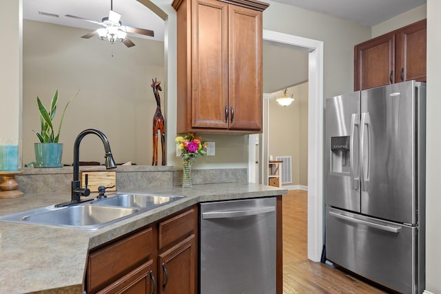 kitchen featuring kitchen peninsula, light wood-type flooring, stainless steel appliances, ceiling fan, and sink