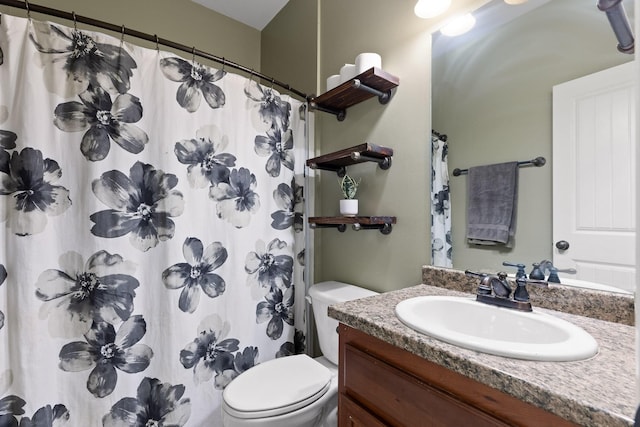 bathroom with walk in shower, vanity, and toilet