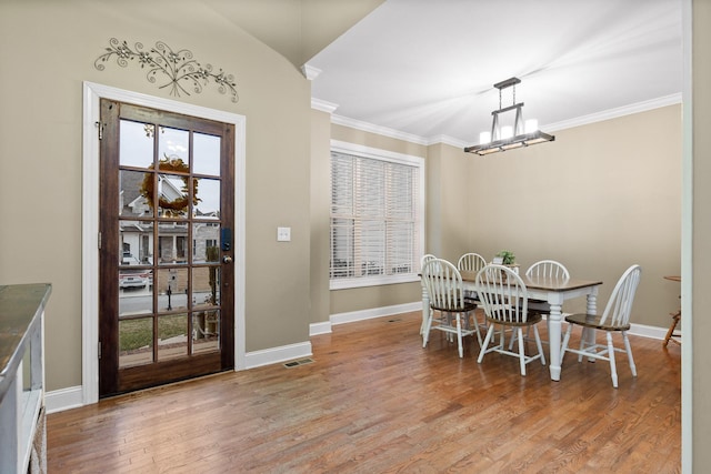 dining room featuring crown molding, an inviting chandelier, and light wood-type flooring