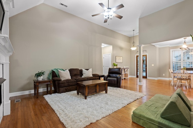 living room with hardwood / wood-style floors, ceiling fan, vaulted ceiling, and decorative columns