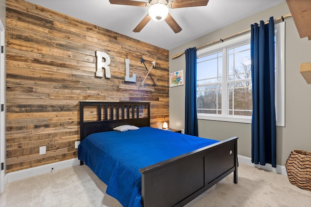 bedroom with ceiling fan, light colored carpet, and wooden walls