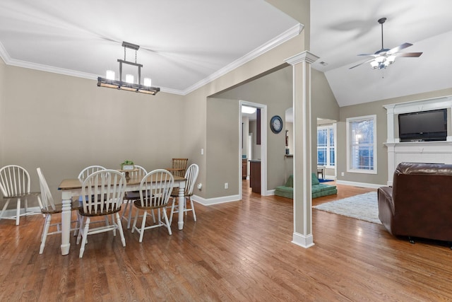 dining space featuring decorative columns, ceiling fan with notable chandelier, crown molding, hardwood / wood-style floors, and lofted ceiling