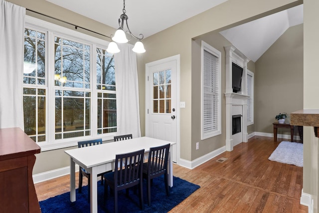 dining room with dark hardwood / wood-style floors, a healthy amount of sunlight, vaulted ceiling, and an inviting chandelier