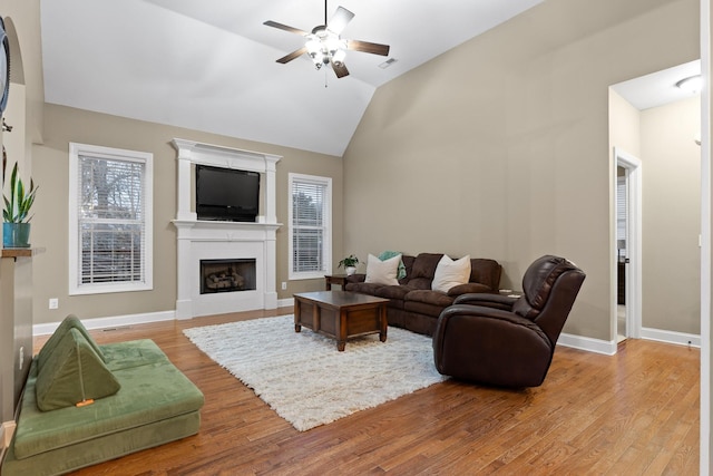 living room with ceiling fan, vaulted ceiling, and light wood-type flooring