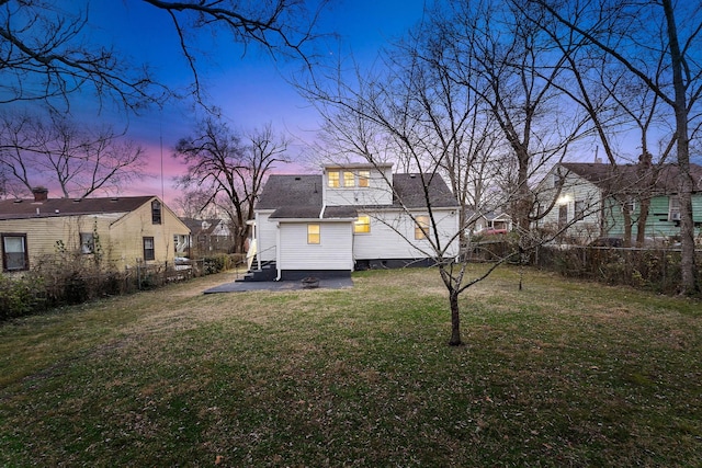 back house at dusk featuring a yard